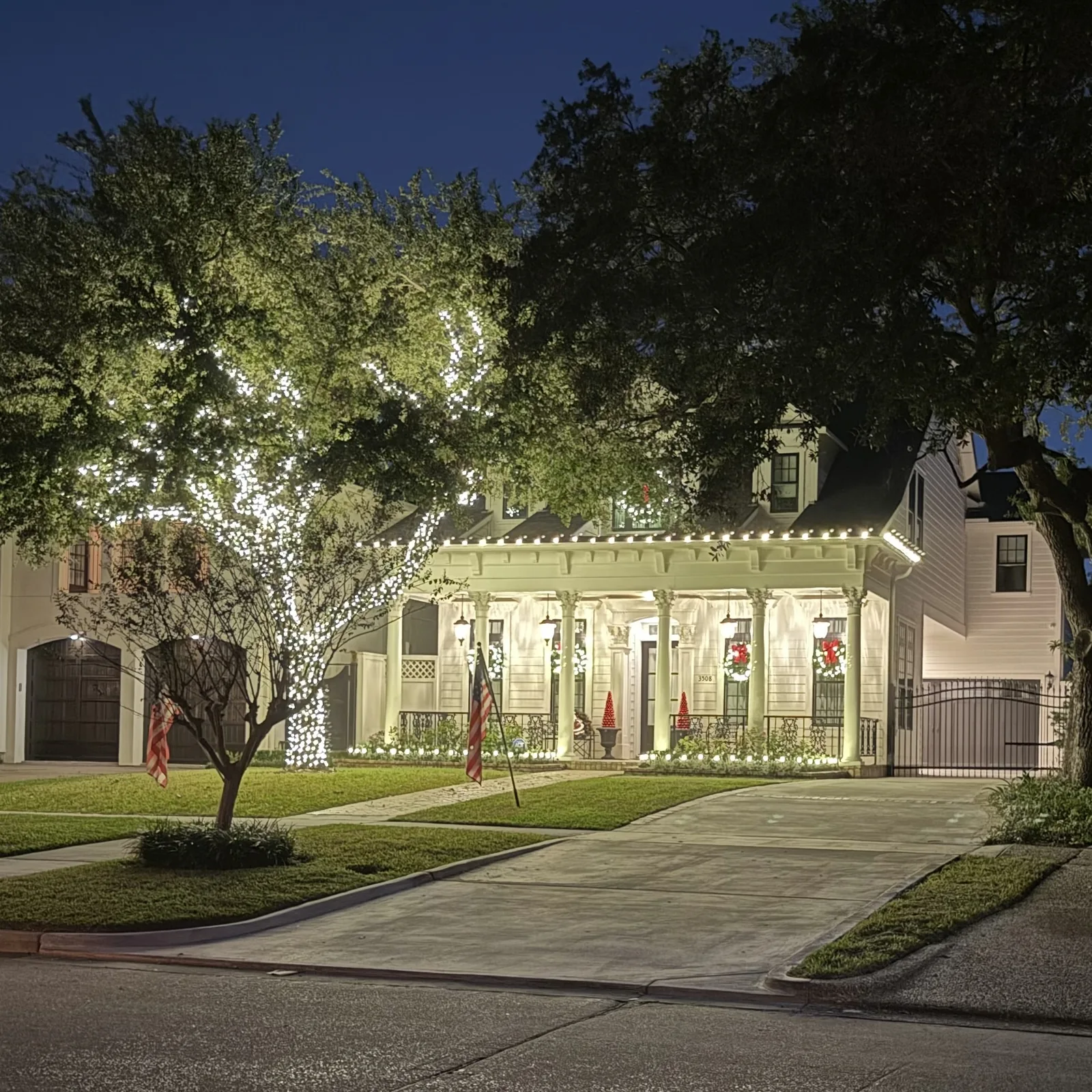 Two-story colonial home with C9-style Christmas roofline lights, window wreaths, and entry garland by The Perfect Light